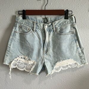 Light wash distressed denim shorts with lace detail. Size 4.